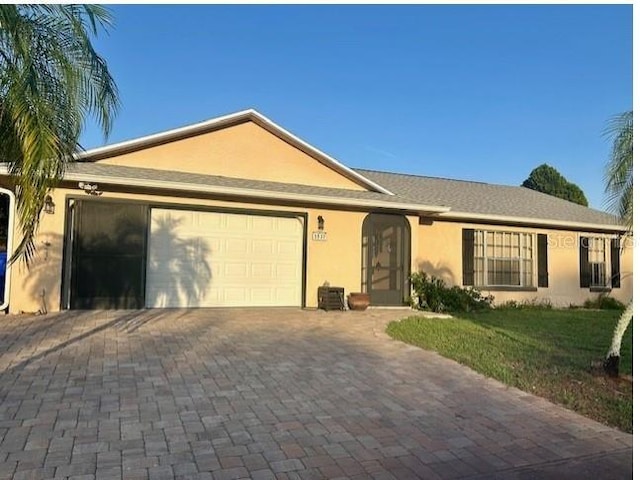 2537 Lanier Rd, Kissimmee, FL 34744 - ranch-style home featuring an attached garage, decorative driveway, stucco siding, and a front yard