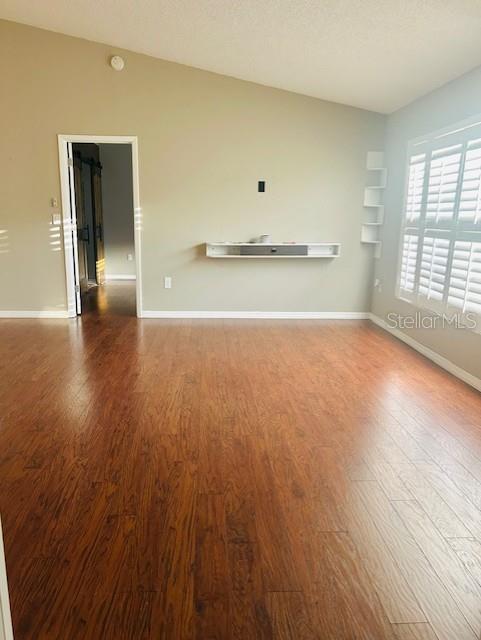 2537 Lanier Rd, Kissimmee, FL 34744 - unfurnished living room with wood finished floors and baseboards