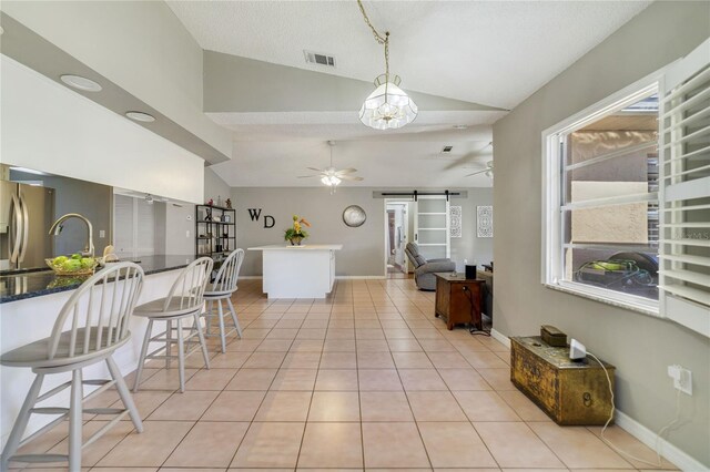 2537 Lanier Rd, Kissimmee, FL 34744 - kitchen with lofted ceiling, a barn door, ceiling fan, light tile patterned flooring, and hanging light fixtures
