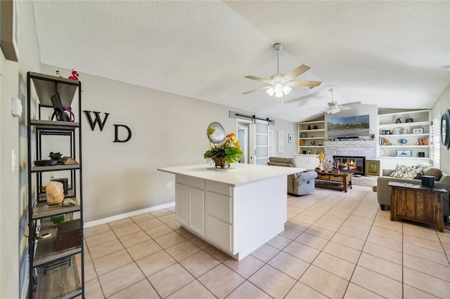 2537 Lanier Rd, Kissimmee, FL 34744 - kitchen featuring a barn door, lofted ceiling, a ceiling fan, light tile patterned flooring, and a textured ceiling