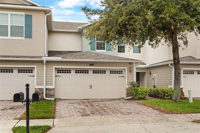 view of property featuring a garage, a shingled roof, decorative driveway, and stucco siding