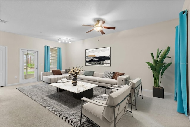 living room with baseboards, visible vents, a ceiling fan, and light colored carpet