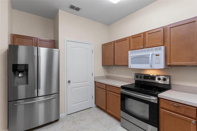 kitchen with light countertops, appliances with stainless steel finishes, brown cabinetry, and visible vents