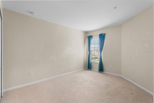 unfurnished room featuring light colored carpet and baseboards