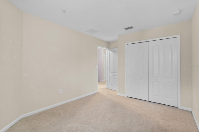 unfurnished bedroom featuring a closet, light colored carpet, visible vents, and baseboards