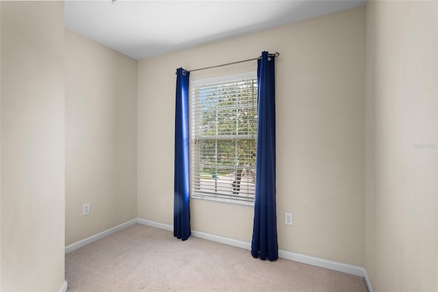 unfurnished room featuring light carpet and baseboards