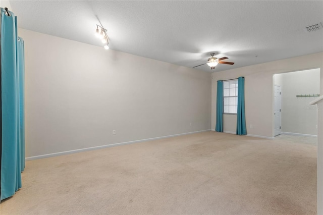 unfurnished room with light carpet, visible vents, ceiling fan, and a textured ceiling