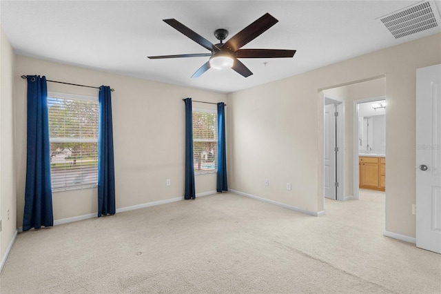 spare room featuring light carpet, plenty of natural light, visible vents, and baseboards