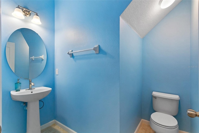 half bathroom with baseboards and toilet