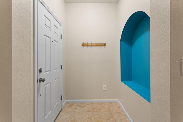 entryway featuring baseboards and light colored carpet