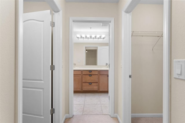 hallway featuring light tile patterned flooring and a sink