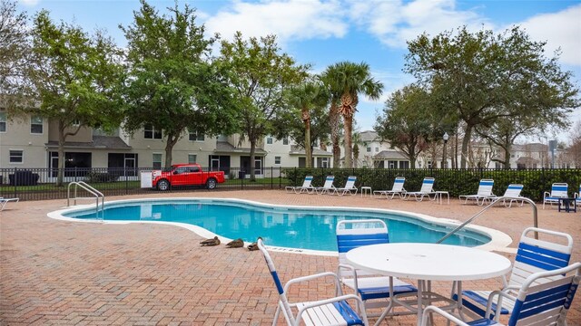 community pool with a patio area, fence, and a residential view