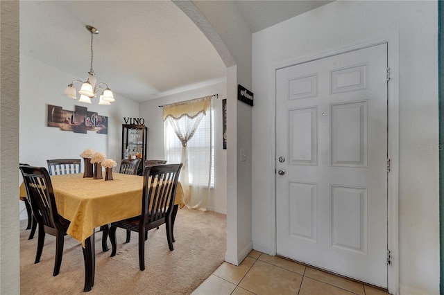 tiled dining space featuring vaulted ceiling and an inviting chandelier