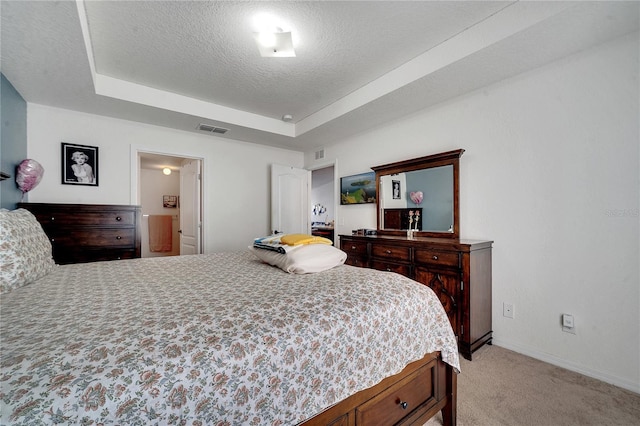 carpeted bedroom with a textured ceiling and a raised ceiling