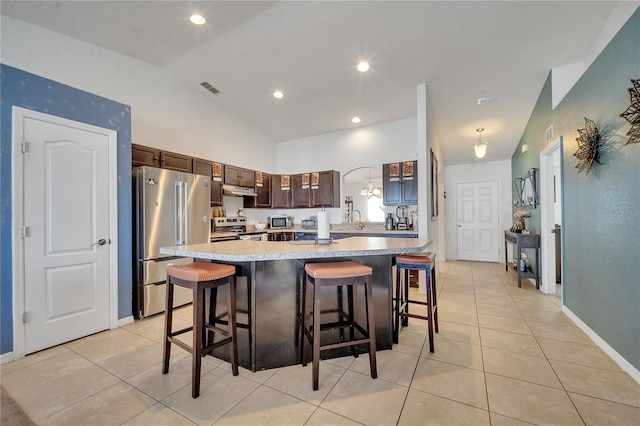 kitchen with dark brown cabinetry, a center island, a kitchen bar, and stainless steel appliances