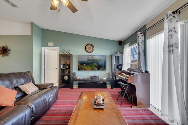 living room with lofted ceiling, ceiling fan, and a textured ceiling