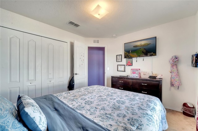 carpeted bedroom featuring a textured ceiling and a closet