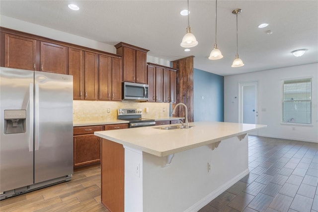 kitchen featuring sink, decorative light fixtures, a kitchen breakfast bar, stainless steel appliances, and a kitchen island with sink