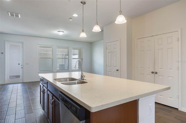 kitchen featuring pendant lighting, stainless steel dishwasher, sink, and a center island with sink