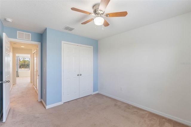 unfurnished bedroom with light colored carpet, ceiling fan, and a closet