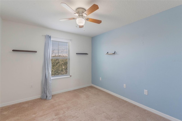 empty room featuring ceiling fan, light carpet, and a textured ceiling