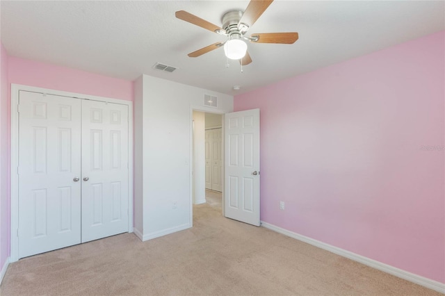 unfurnished bedroom with light carpet, a closet, and ceiling fan