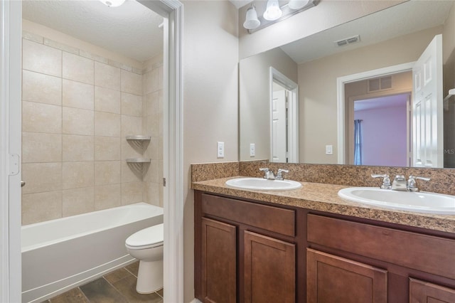 full bathroom with vanity, tiled shower / bath combo, a textured ceiling, and toilet