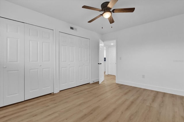 unfurnished bedroom with multiple closets, ceiling fan, and light wood-type flooring