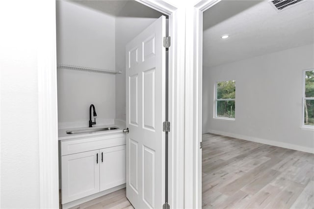 bar with recessed lighting, a sink, visible vents, baseboards, and light wood finished floors