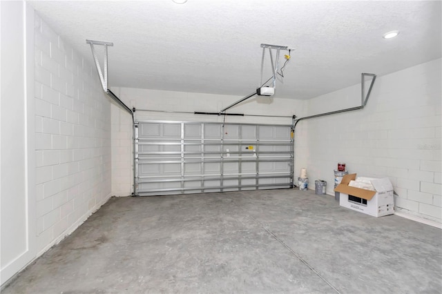 garage featuring concrete block wall and a garage door opener