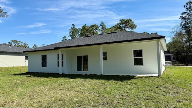 back of property with a shingled roof, a lawn, and stucco siding