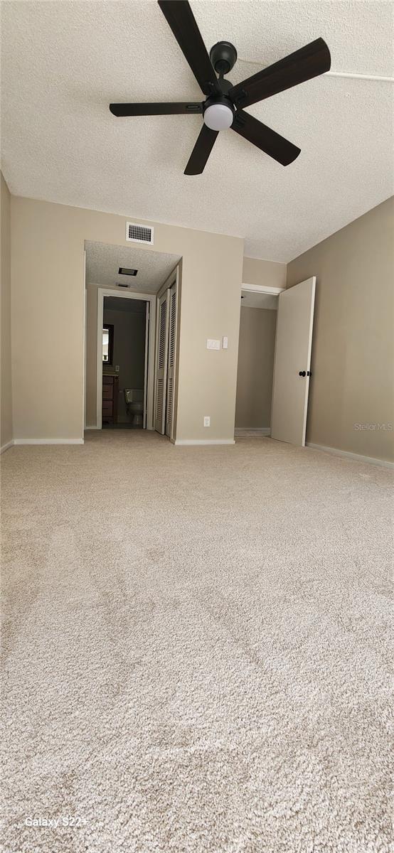 spare room featuring ceiling fan, carpet floors, and a textured ceiling