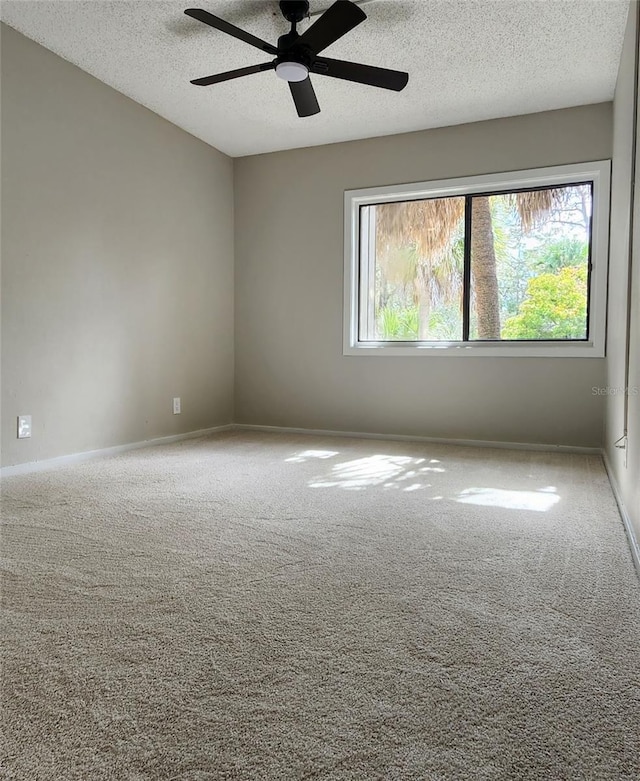 carpeted empty room with ceiling fan, a textured ceiling, and a healthy amount of sunlight