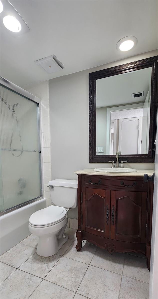 full bathroom with vanity, tile patterned floors, combined bath / shower with glass door, and toilet