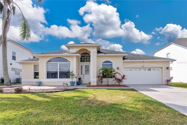 view of front of home with a garage, central AC, and a front yard