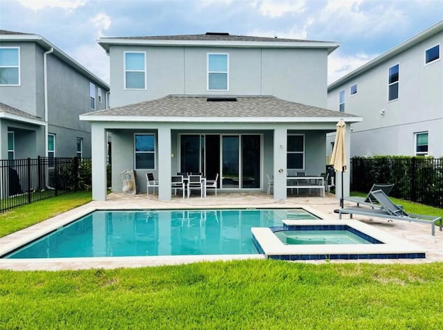 back of property featuring a pool with hot tub, a patio area, and a lawn