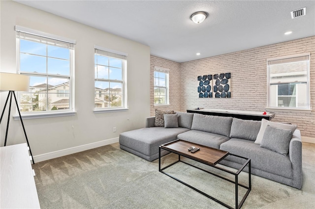 living room featuring brick wall, carpet flooring, a textured ceiling, and a wealth of natural light