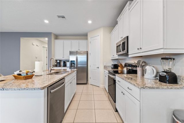 kitchen with sink, white cabinets, a kitchen island with sink, light tile patterned floors, and stainless steel appliances