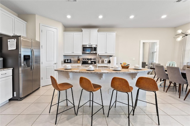 kitchen with a kitchen island with sink, stainless steel appliances, and white cabinets