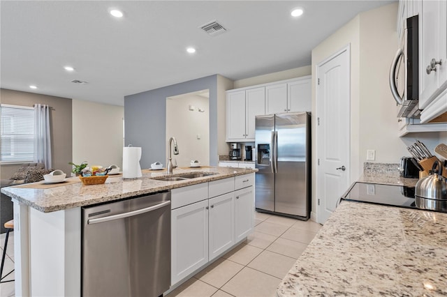 kitchen with an island with sink, stainless steel appliances, sink, and white cabinets