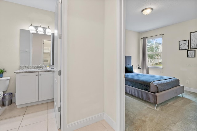 tiled bedroom with connected bathroom and sink