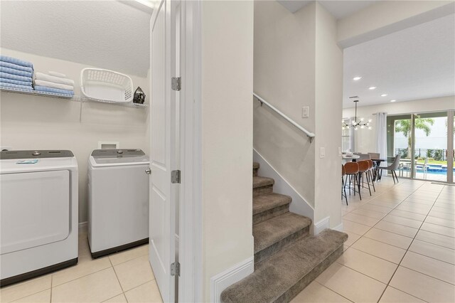 washroom featuring light tile patterned flooring, a notable chandelier, and washer and clothes dryer