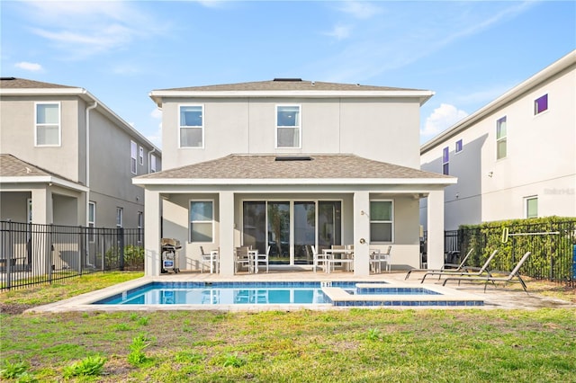 back of property with a yard, a pool with hot tub, and a patio area