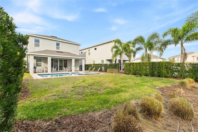 rear view of house with a yard, a fenced in pool, and a patio