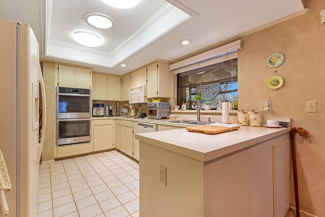 kitchen with crown molding, appliances with stainless steel finishes, cream cabinets, kitchen peninsula, and a raised ceiling