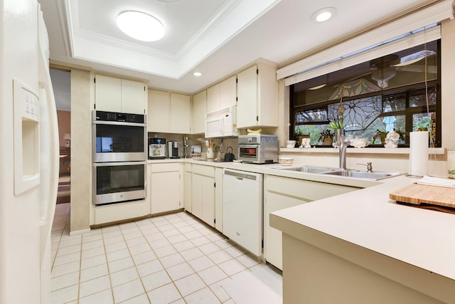 kitchen featuring sink, ornamental molding, light tile patterned floors, a tray ceiling, and white appliances