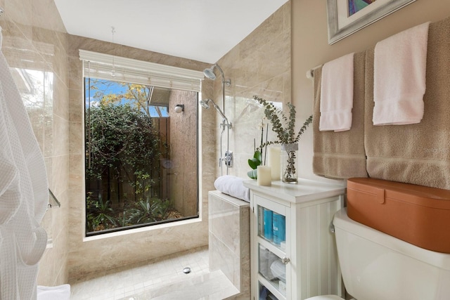 bathroom with a tile shower and toilet