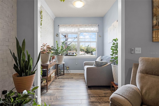 living area featuring brick wall and dark hardwood / wood-style flooring