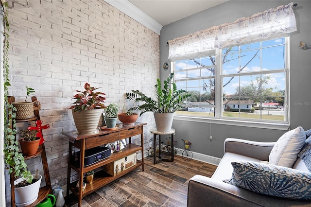 living area with ornamental molding and brick wall