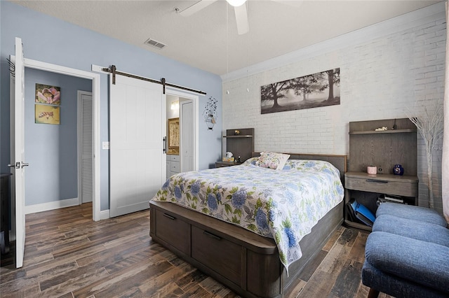 bedroom featuring dark wood-type flooring, brick wall, a barn door, and a textured ceiling